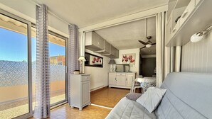 A modern living room with a sofa, a dining area, and a kitchen. - CAP D'AGDE - Plage Richelieu // Réf 0157 (CAP D'AGDE)