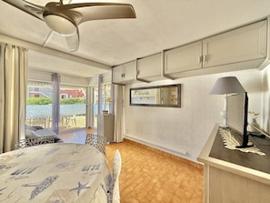 Ein Hotelzimmer mit Bett, Schreibtisch, Deckenventilator, einem großen Fenster und Blick ins Freie.