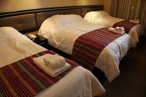 A hotel room with three beds, each with a striped blanket and rolled towels. - Triple Room - Tampu Hotel. (Cusco)