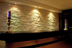 Un área de recepción con pared de piedra, mostrador de recepción y un pilar decorativo.
