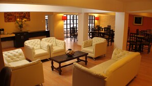 Ampla sala de estar com sofá, mesa de centro e área de jantar com cadeiras e mesas.