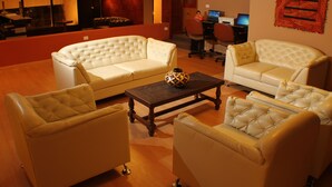 Uma sala de estar com sofá, mesa de centro e escrivaninha com dois monitores.