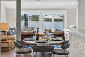 Un coin repas avec une table dressée pour quatre personnes, un canapé et une vue sur un lac.