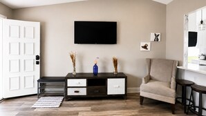 Una sala de estar con televisor, sofá, mesa de centro y aparador.