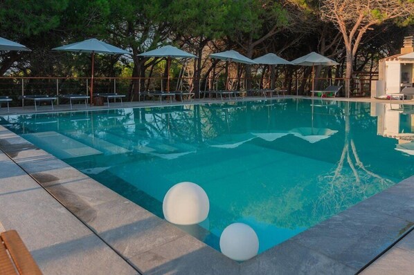 A swimming pool with lounge chairs and umbrellas, surrounded by trees. - Q Resort Hotel (Sorso)