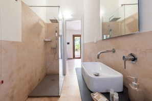 A modern bathroom with a walk-in shower, a standalone bathtub, and a large mirror. - Q Resort Hotel (Sorso)
