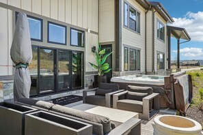 Eine moderne Außenpatio mit Whirlpool, Sitzgelegenheit und großem Fenster mit Blick auf eine Landschaft.