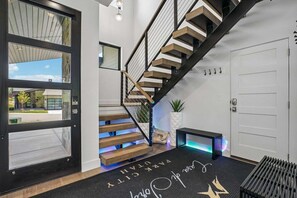 Eine moderne Treppe mit Holzstufen und Metallgeländern, eine schwarze Tür mit Fensterfeldern und eine Fußmatte mit dem Schriftzug 'Welcome to Park City'.