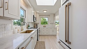 A modern kitchen with white cabinetry, a large window, and a skylight. - Casa del Sol | Pickle ball court| Fire pit | Dock | Sleeps 10 (Mooresville)