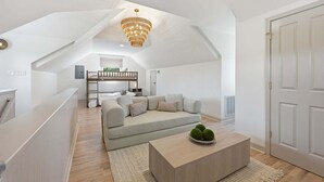 A modern loft bedroom with a sloped ceiling, a built-in bed, a sofa, and a coffee table. - Casa del Sol | Pickle ball court| Fire pit | Dock | Sleeps 10 (Mooresville)
