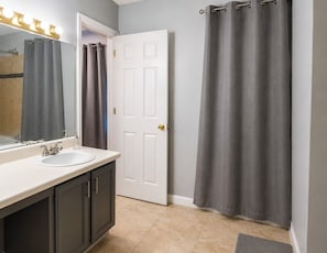 A bathroom with a white sink, mirror, and a shower curtain. -     Quiet & Comfortable • Close to Atlanta Attractions (Marietta)