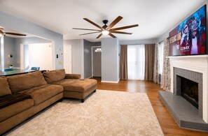 A living room with a sectional sofa, a fireplace, and a ceiling fan. -     Quiet & Comfortable • Close to Atlanta Attractions (Marietta)