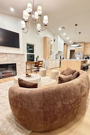 Ein modernes Wohnzimmer mit einer gebogenen Couch, einem Kamin und einem Essbereich.