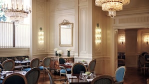 En elegant spisesal med lysekroner, et stort spejl og en buffet.