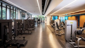 Ett modernt gym med olika träningsmaskiner, stora fönster och en ren och väl upplyst interiör.
