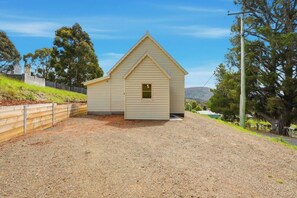 A small, single-story building with a gabled roof, a front door, and a small window. - Converted Church Escape (Collinsvale)