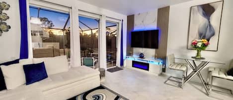 Un salón moderno con un sofá blanco, una mesa de centro de vidrio y un ventanal grande.