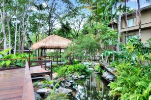 A wooden deck, a thatched-roof pavilion, and a pond surrounded by lush greenery. - [TROPICS] Ramada Resort & Spa 🏝 Free Wifi in Room (Port Douglas)