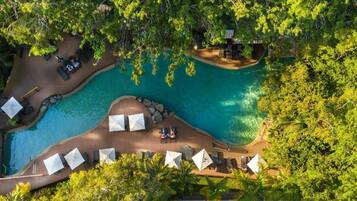 An aerial view of a resort with a swimming pool, lounge chairs, and umbrellas.