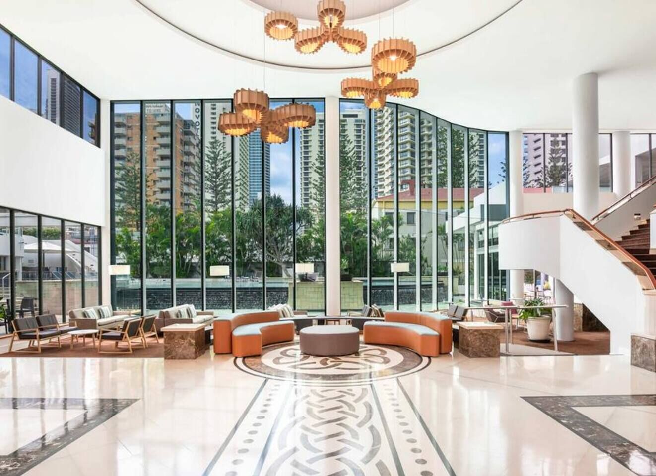 A spacious lobby with a central seating area, large windows, and a staircase.
