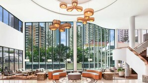 A spacious lobby with a central seating area, large windows, and a staircase. - [OCEAN SIDE] North East Ocean View Twin @ Mantra (Surfers Paradise)