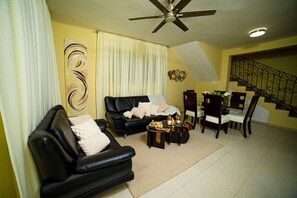 Ein Wohnzimmer mit einer schwarzen Ledersofa, einem Couchtisch und einem Essbereich mit Stühlen und einem Tisch.