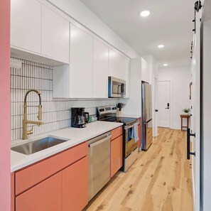 A modern kitchen with white cabinets, a stainless steel sink, a gold faucet, a microwave, and a refrigerator. - Fifa Stay 5 Min Walk Met Sleeps 5 3 Beds Gym (Philadelphia)