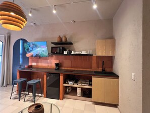 Eine moderne Küche mit Flachbildfernseher, Kaffeemaschine und Spüle.