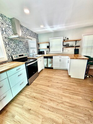 Eine moderne Küche mit ornamentalem Rücksprühen, Edelstahlgeräten und Holzboden.