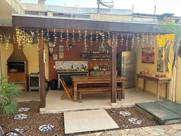 A patio with a wooden table and chairs, a built-in oven, and a refrigerator.