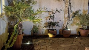 A courtyard with potted plants, a stone floor, and a white wall. - Flats Brisapart (Ubatuba)