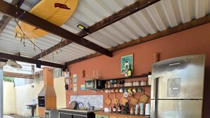 A rustic kitchen with a wooden table, a refrigerator, and various kitchen utensils. - Flats Brisapart (Ubatuba)