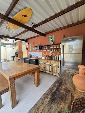 A rustic kitchen with a wooden table, a refrigerator, and various kitchen utensils.