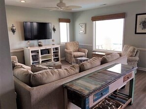 Ein Wohnzimmer mit einer Sofagarnitur, einem Couchtisch, einem Fernseher und einem Bücherregal.