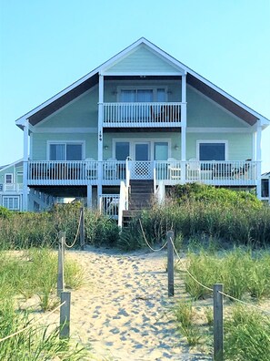 Ein zweistöckiges Strandhaus mit Balkon, einer Haustür und der deutlich sichtbaren Nummer 199 an der Seite.