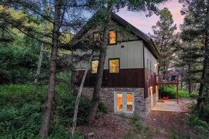 Ein modernes Haus mit Steinfundament, großen Fenstern und einer Holzterrasse.