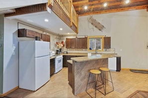 A modern kitchen with a central island, wooden cabinets, and a built-in oven. - Two Top Stop | 15min to Yellowstone, Hot Tub, Arcades, BBQ! (Island Park)