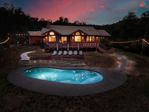 Ein Haus mit Pool, Liegestühlen und Lichterkette.