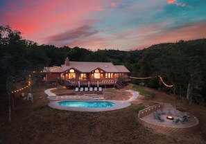 Ein Haus mit Swimmingpool, Liegestühlen und Lichterketten.