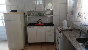 A compact kitchen with white cabinets, a refrigerator, a stove, and a sink. - Quiet corner (Igarapé)