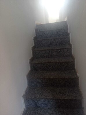 Una escalera con barandilla que sube a un piso superior.