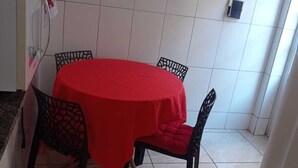 A dining area with a round table covered in a red tablecloth, surrounded by four chairs. - Quiet corner (Igarapé)