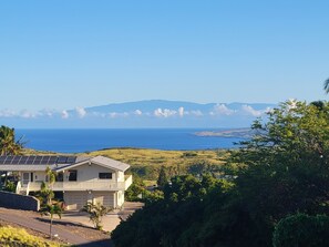 Ein Haus mit Solaranlage, Garage und Blick auf Meer und Berge.