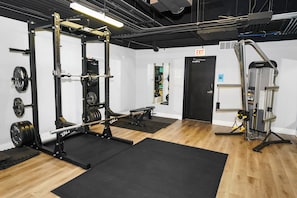 A gym with weightlifting equipment, a bench, and a door marked "EXIT".