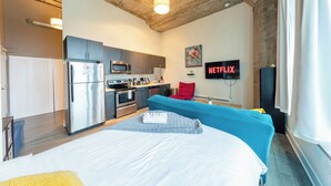 A modern hotel room with a kitchenette, a bed, a flat-screen TV, and a large window. - McCormick Place Modern Suite for 4, with Optional Parking (Chicago)