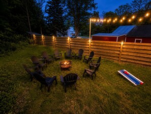 Patio trasero con un brasero, sillas y una mesa para jugar shuffleboard.