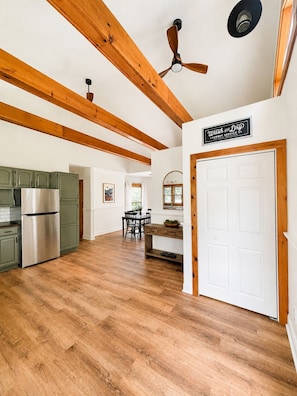 A spacious kitchen with wooden beams, a ceiling fan, and a sign for a laundry service.
