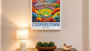 Un cartel enmarco de Cooperstown, Nueva York, sobre una consola de madera oscura con una lámpara y adornos.