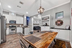 A modern kitchen with stainless steel appliances, a wooden dining table, and a Houston Astros sign on the wall.