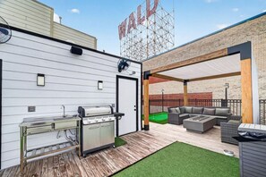An outdoor patio with a grill, seating area, and a brick wall.